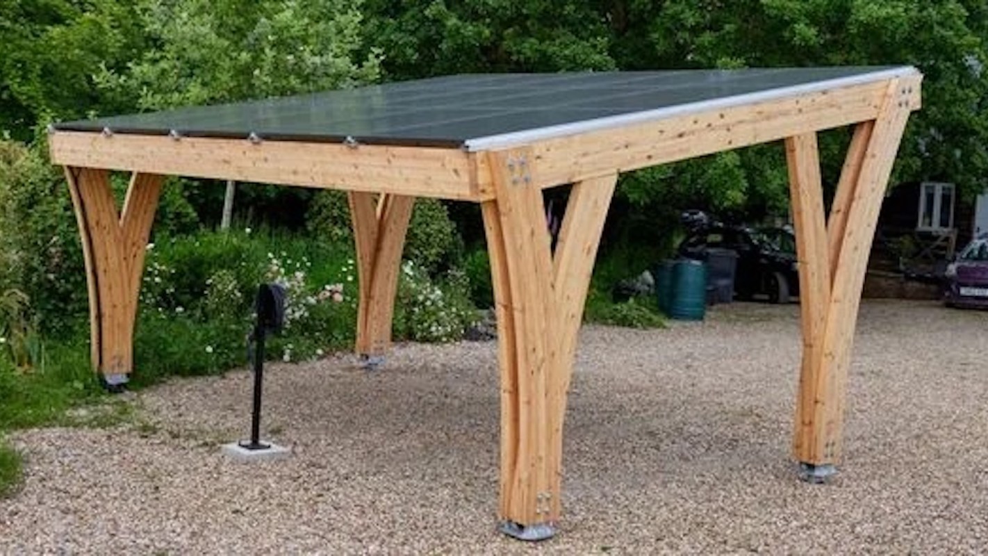 A wooden structure with a solar panel roof in a garden setting.