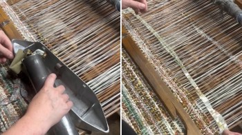 A person is using a weaving tool on a loom with colorful threads.
