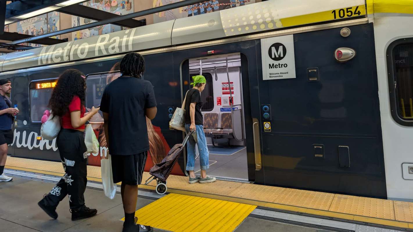 A group of people entering a Metro Rail train at a transit station.