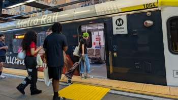 A group of people entering a Metro Rail train at a transit station.