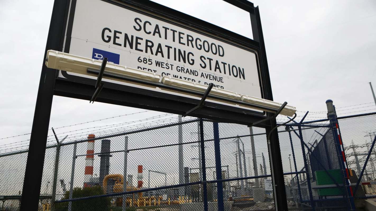 A sign for Scattergood Generating Station near a fenced industrial area.