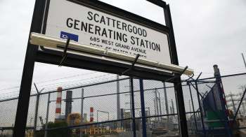 A sign for Scattergood Generating Station near a fenced industrial area.
