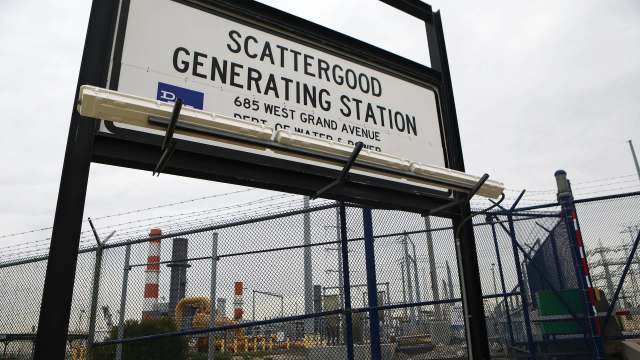 A sign for Scattergood Generating Station near a fenced industrial area.