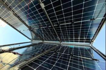 Solar panels installed on a structure, viewed from below against a clear sky.
