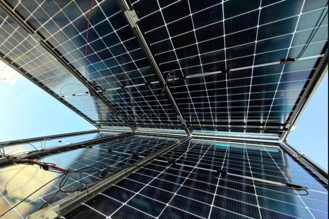 Solar panels installed on a structure, viewed from below against a clear sky.