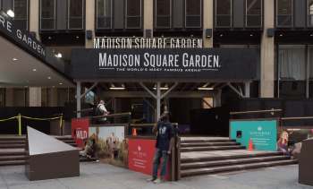 The entrance to Madison Square Garden with people and advertising displays visible.