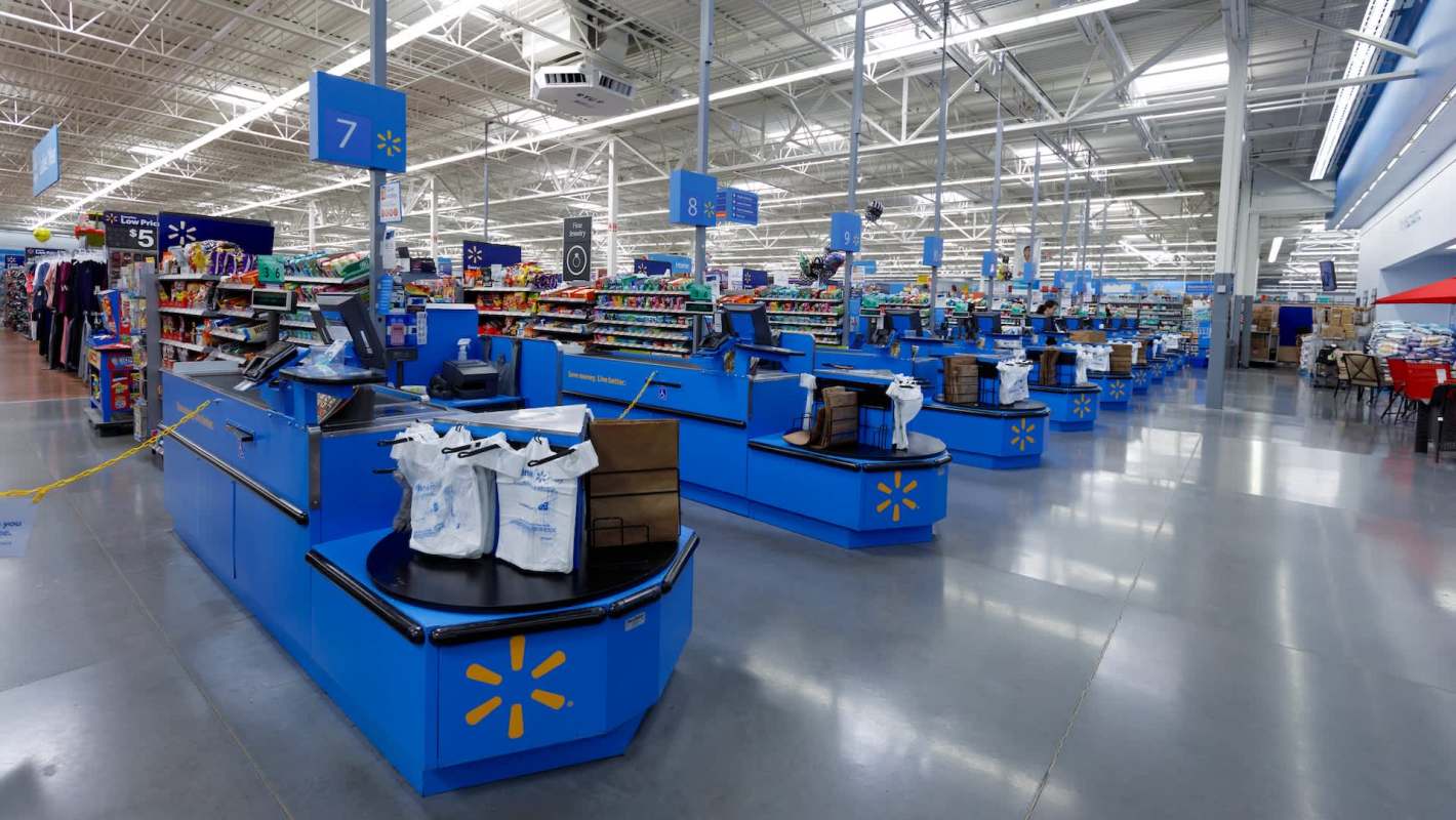 A view of a Walmart checkout area with multiple cash registers and shelves filled with products.