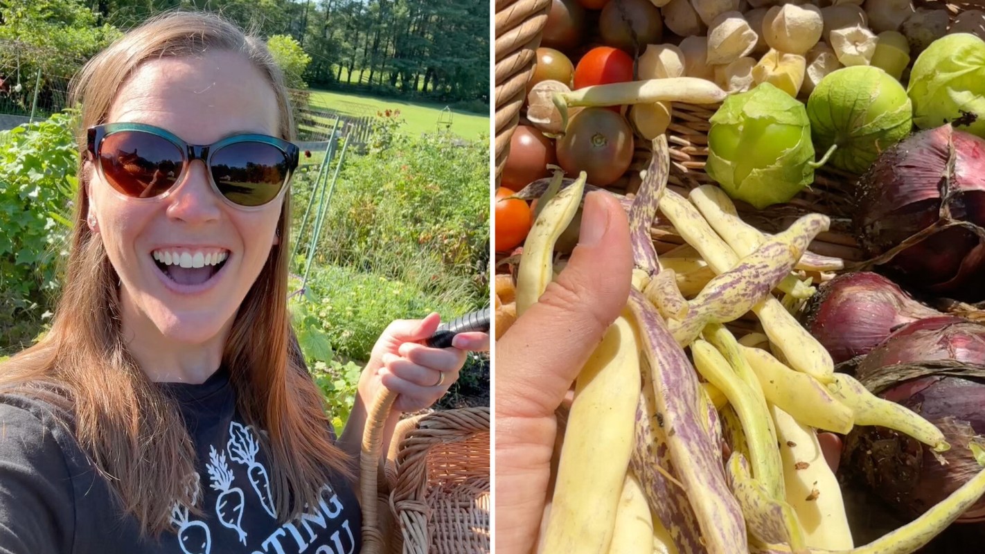A woman in a garden holds a basket filled with various harvested vegetables.