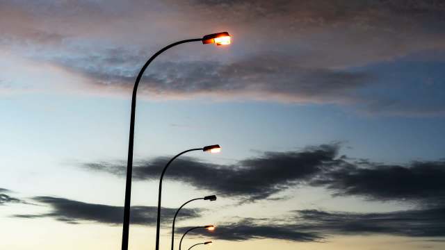 Streetlights illuminated against a twilight sky with clouds.
