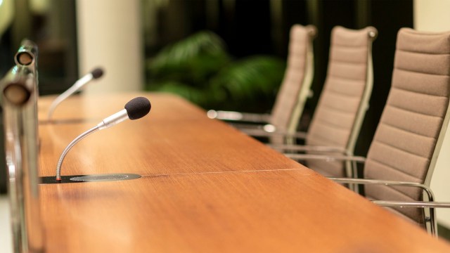 A conference table with microphones and empty chairs in a meeting room.
