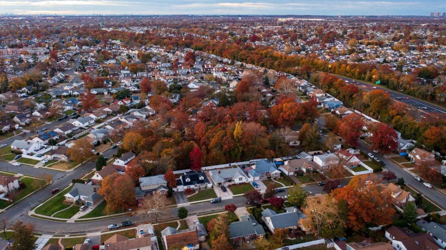 An aerial view of a suburban neighborhood with houses and autumn-colored trees.