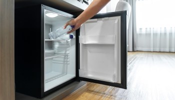 A person places a water bottle into the open compartment of a refrigerator.