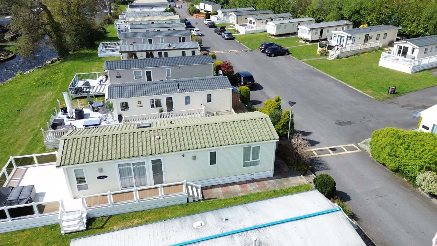 Aerial view of a mobile home park with several units and landscaped areas along a road.