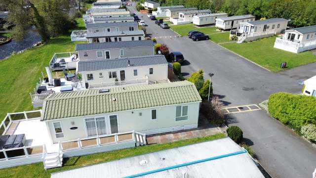 Aerial view of a mobile home park with several units and landscaped areas along a road.