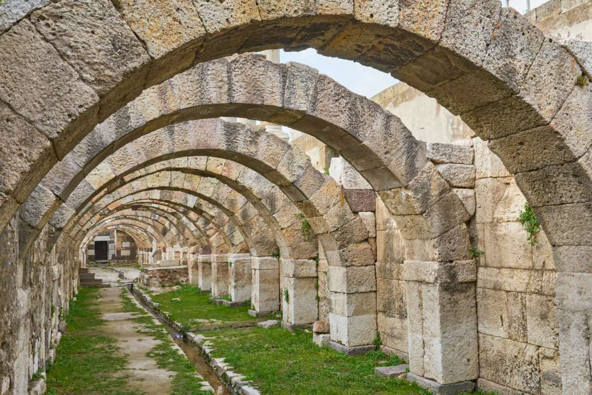 An interior view of stone arches in a historic ruin, with a pathway and grass in the foreground.