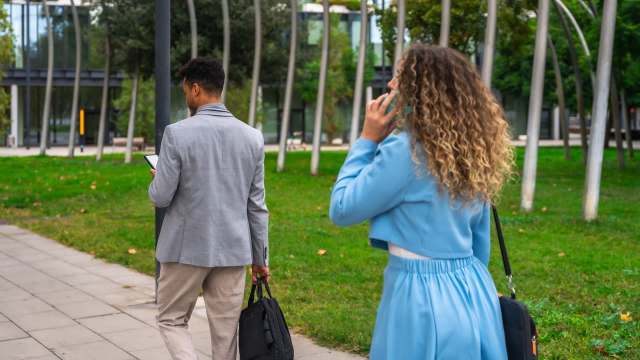 Two people using their phones on a walking path.