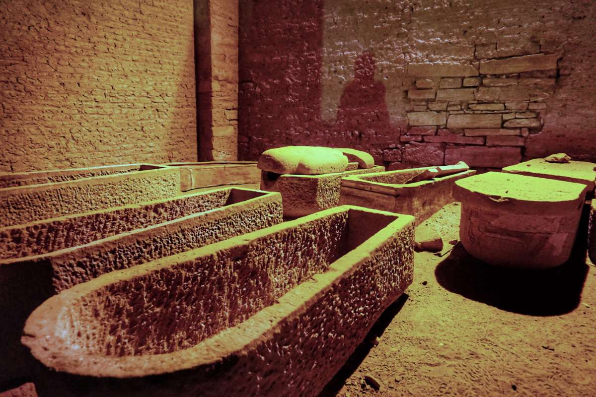 A dimly lit room containing stone coffins and artifacts.
