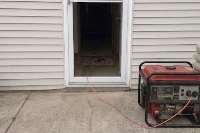 A generator is positioned outside a doorway with a power cable running inside.