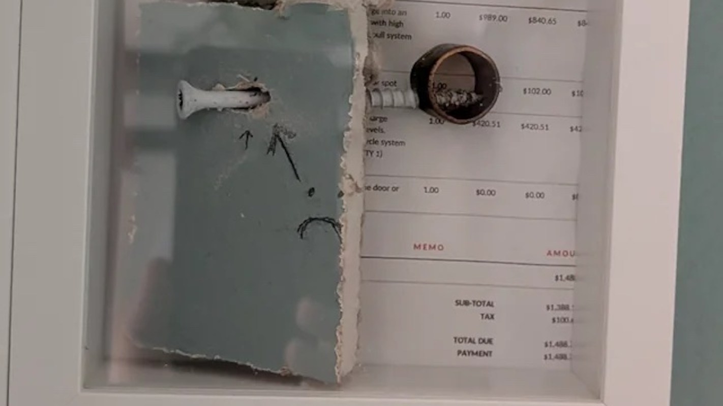 A damaged wall section with a visible screw and a circular pipe next to a printed invoice.