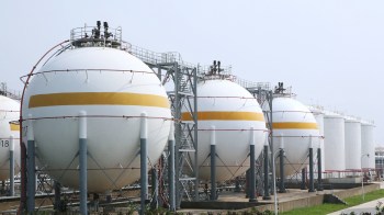 Several large, spherical storage tanks are lined up, featuring yellow stripes and metal frameworks.