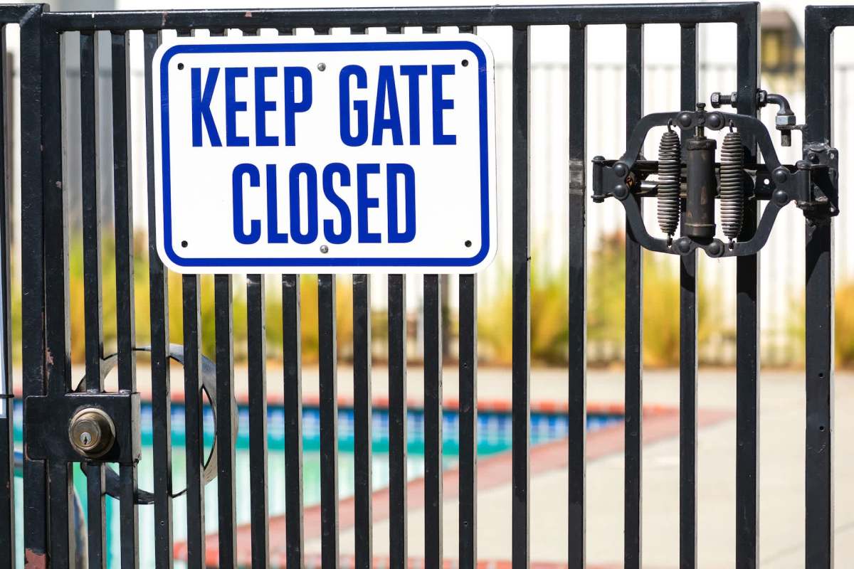 A gate to a swimming pool with a sign that says "KEEP GATE CLOSED" attached to it.