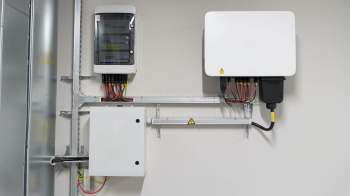 Two electrical panels mounted on a wall with various wires and connectors.