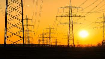 Silhouetted transmission towers and power lines at sunset.