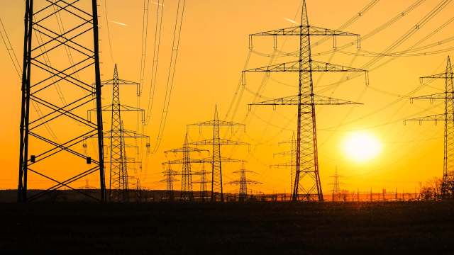 Silhouetted transmission towers and power lines at sunset.