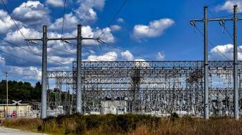 A power substation with transmission towers and clouds in the background.