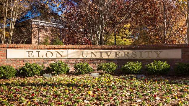 Elon University sign in front of a landscaped area with flowers and shrubs.