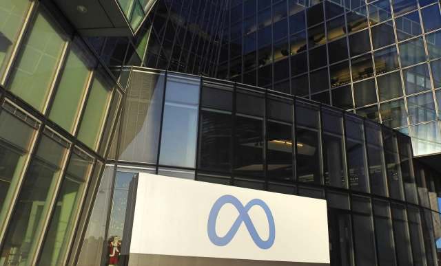 A modern building with large glass windows featuring a sign with Meta's blue infinity logo.