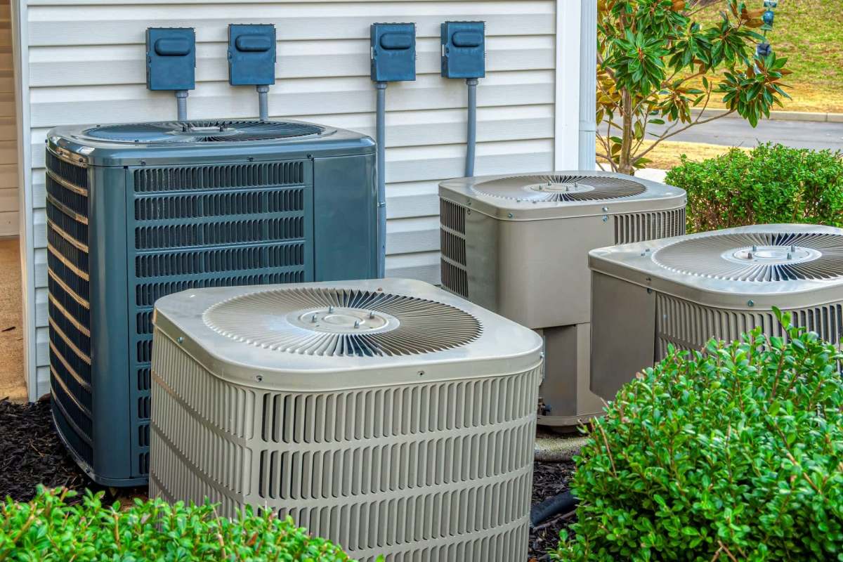 Four AC units outside of an apartment complex.
