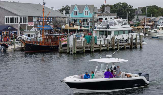 A marina scene with boats and colorful buildings filled with people along the waterfront.