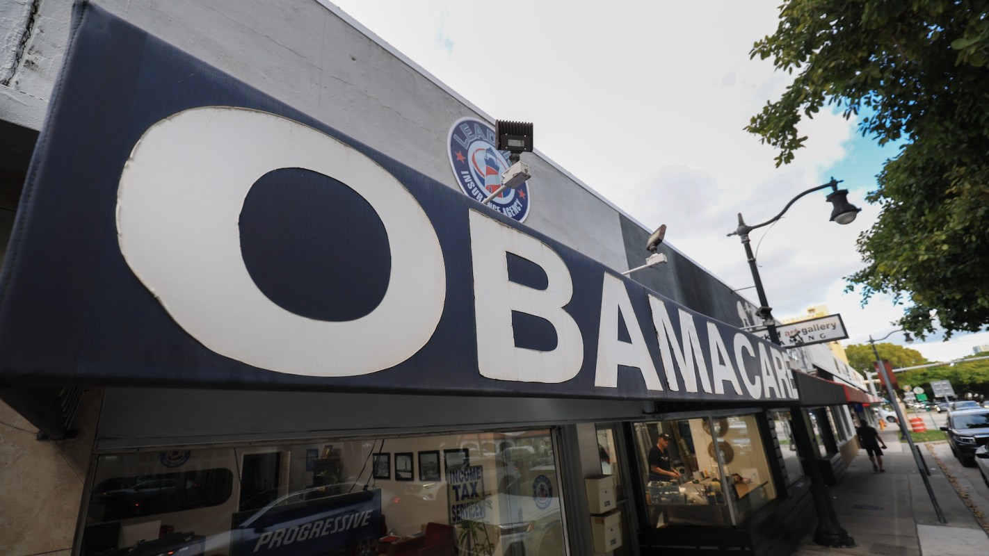 A sign displaying the word "OBAMACARE" on a building storefront.
