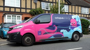 A pink and blue van with an octopus graphic and the logo "octopus energy" parked by a residential area.