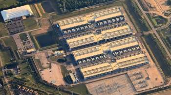 An aerial view of a large industrial complex with several buildings and surrounding green areas.