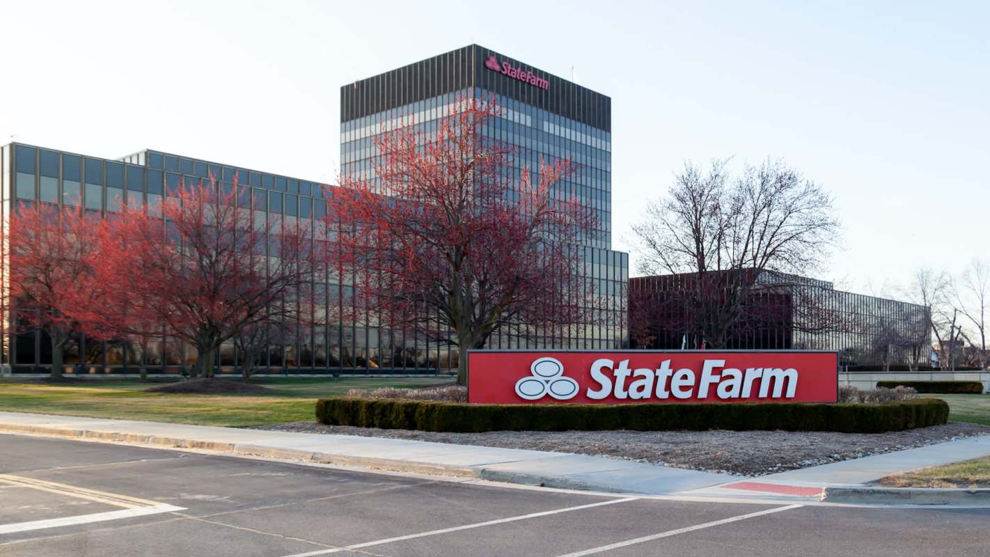 A State Farm office building with a prominent sign and trees in the foreground.