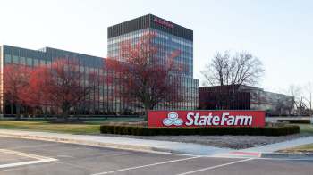 A State Farm office building with a prominent sign and trees in the foreground.