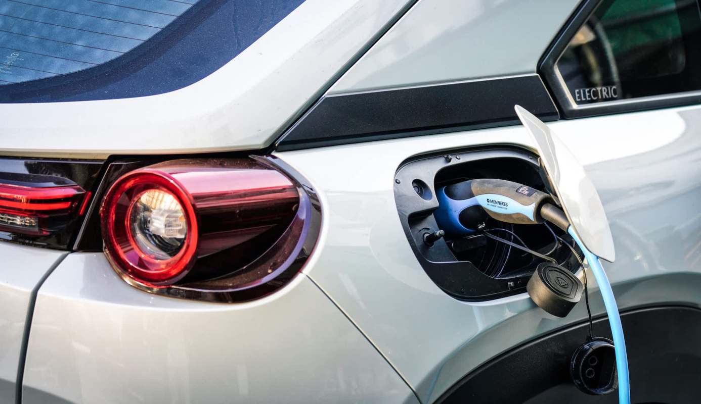 An electric vehicle is plugged into a charging port at the rear.