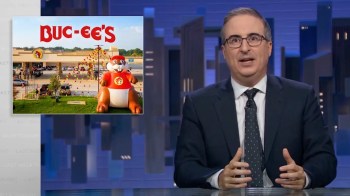 John Oliver speaks in front of a screen displaying a Buc-ee's gas station and a large beaver mascot.