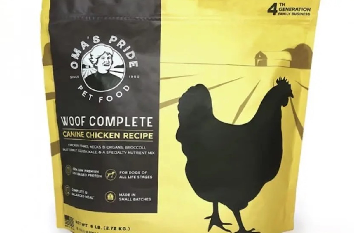 A bag of Oma's Pride pet food labeled "Woof Complete Canine Chicken Recipe" with a chicken silhouette graphic.