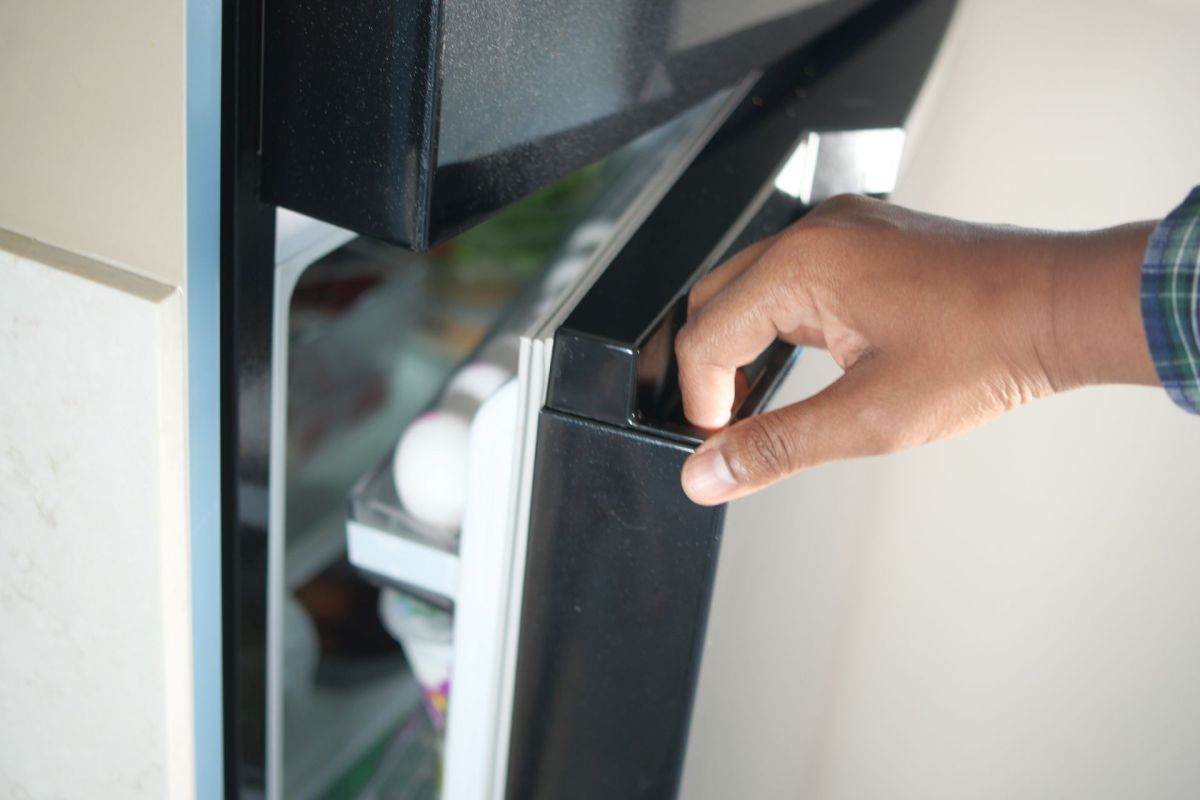 A hand opens a refrigerator door