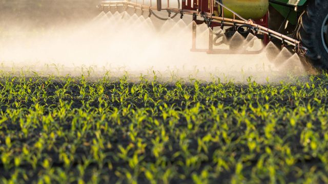 A tractor spraying pesticides on farmland.