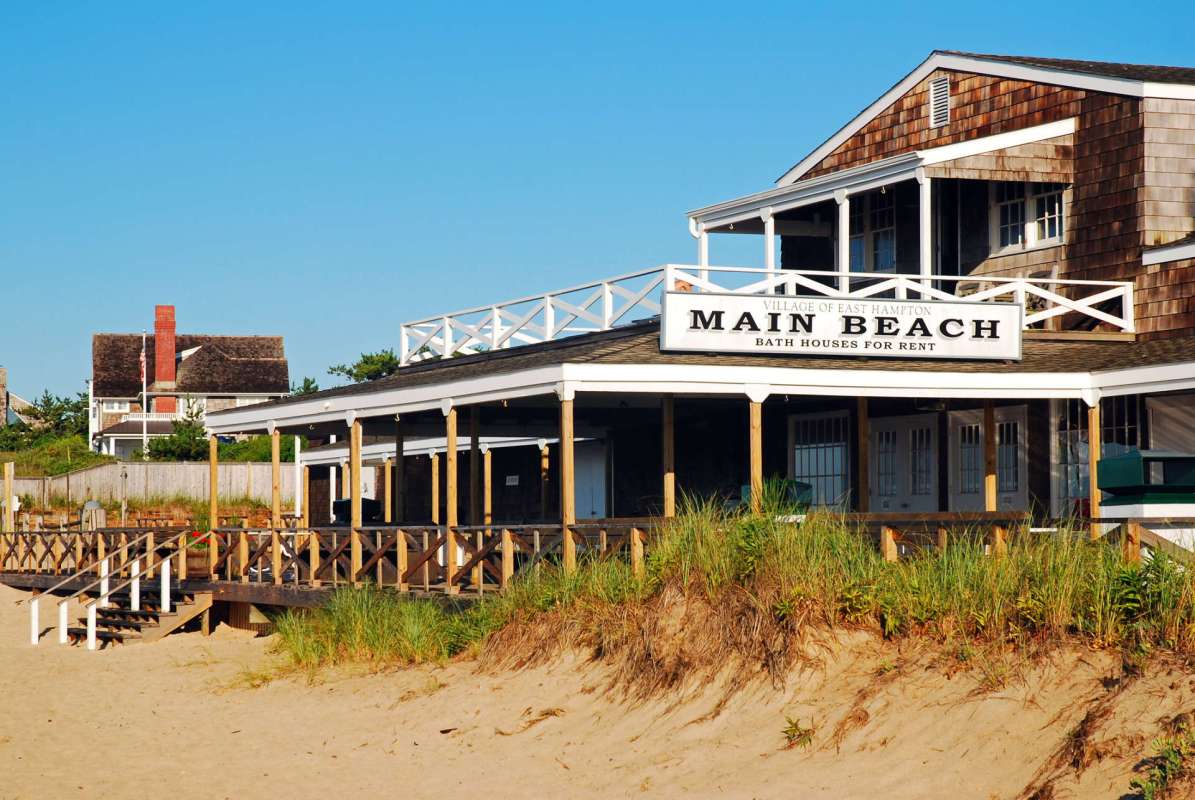 A beachside building with a sign reading "Main Beach" and bath houses for rent.