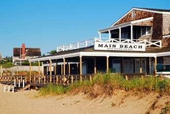 A beachside building with a sign reading "Main Beach" and bath houses for rent.