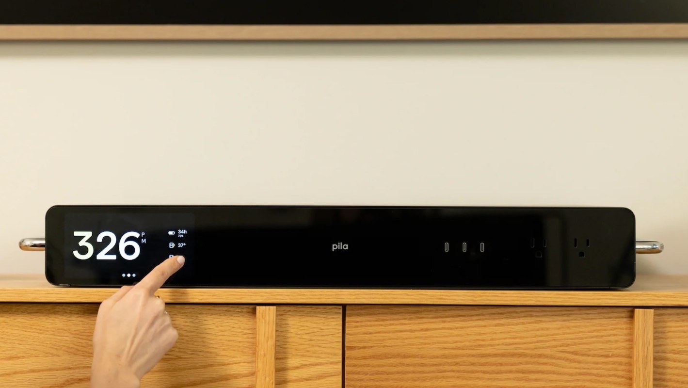 A Pila home battery system displaying time and settings on a wooden surface.