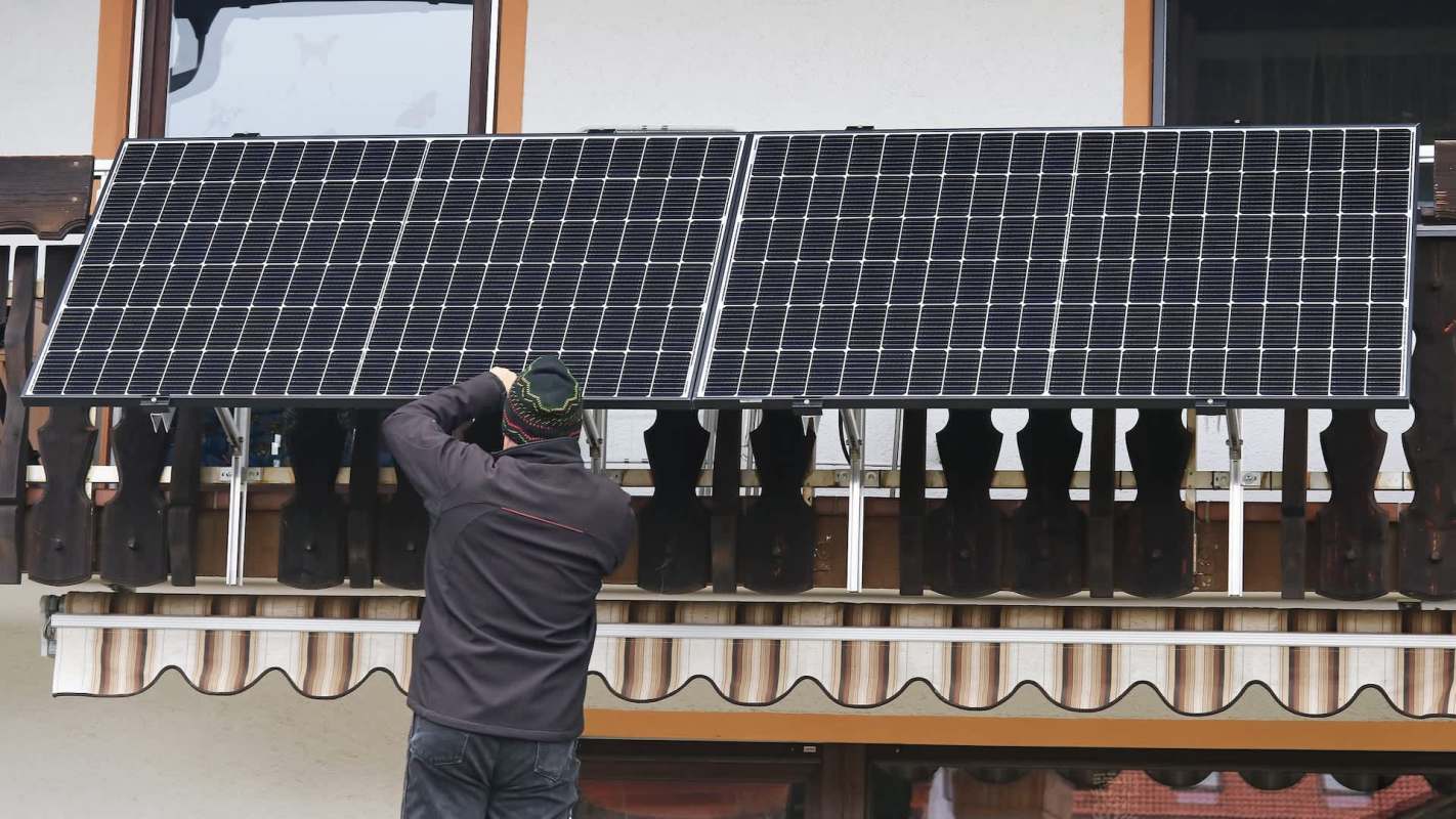A person installs solar panels on a balcony.