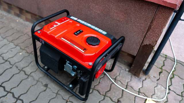 A portable generator on a paved surface near a wall.