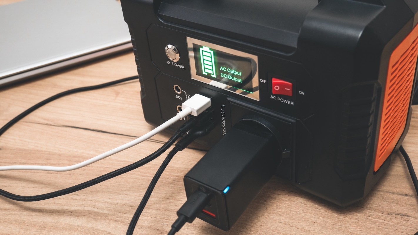 A power station with charging cables connected to various ports on a wooden surface.