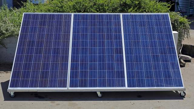 Three solar panels on a frame with wheels.